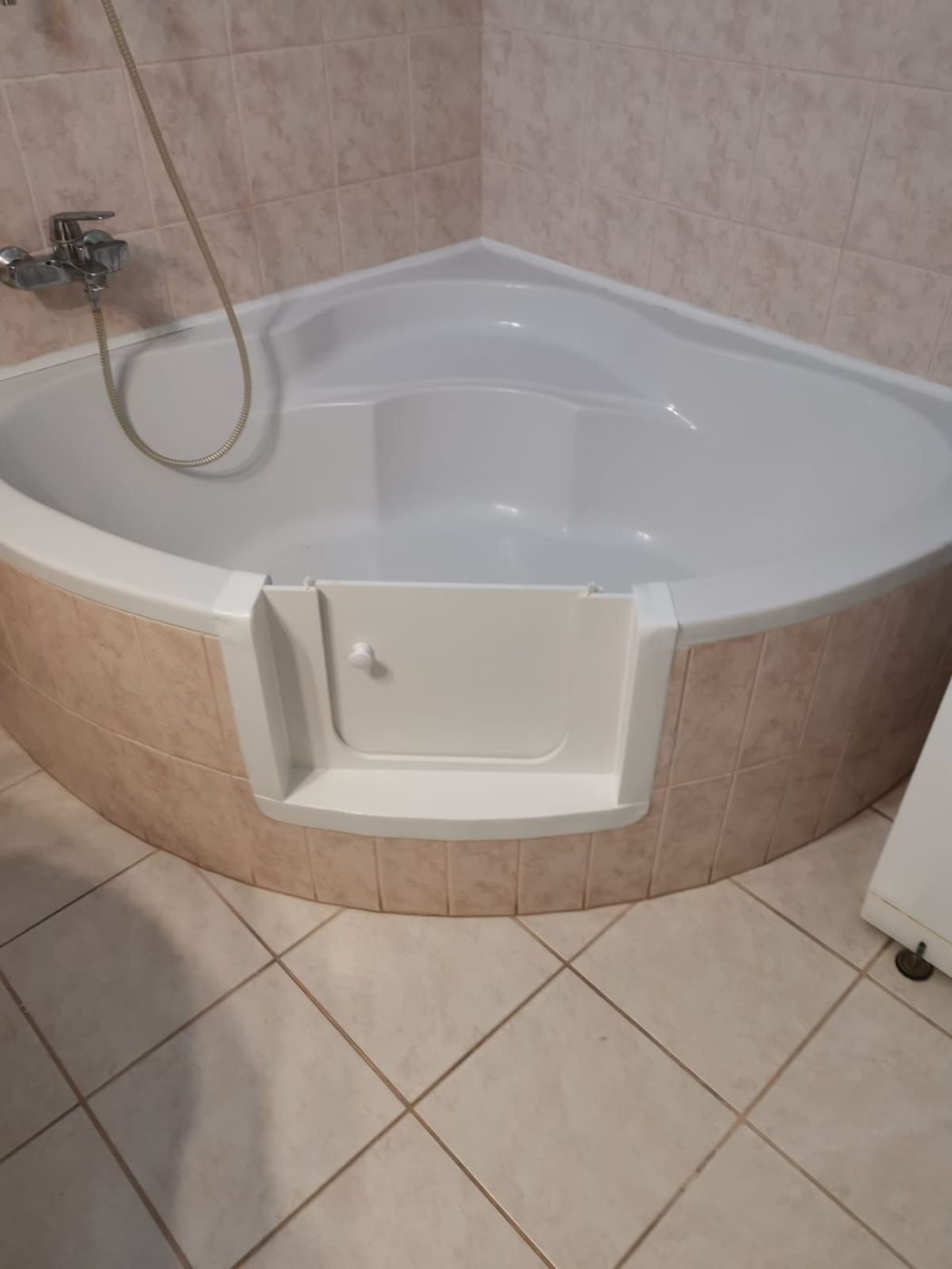 Baddeur in een hoekbad met beige tegels