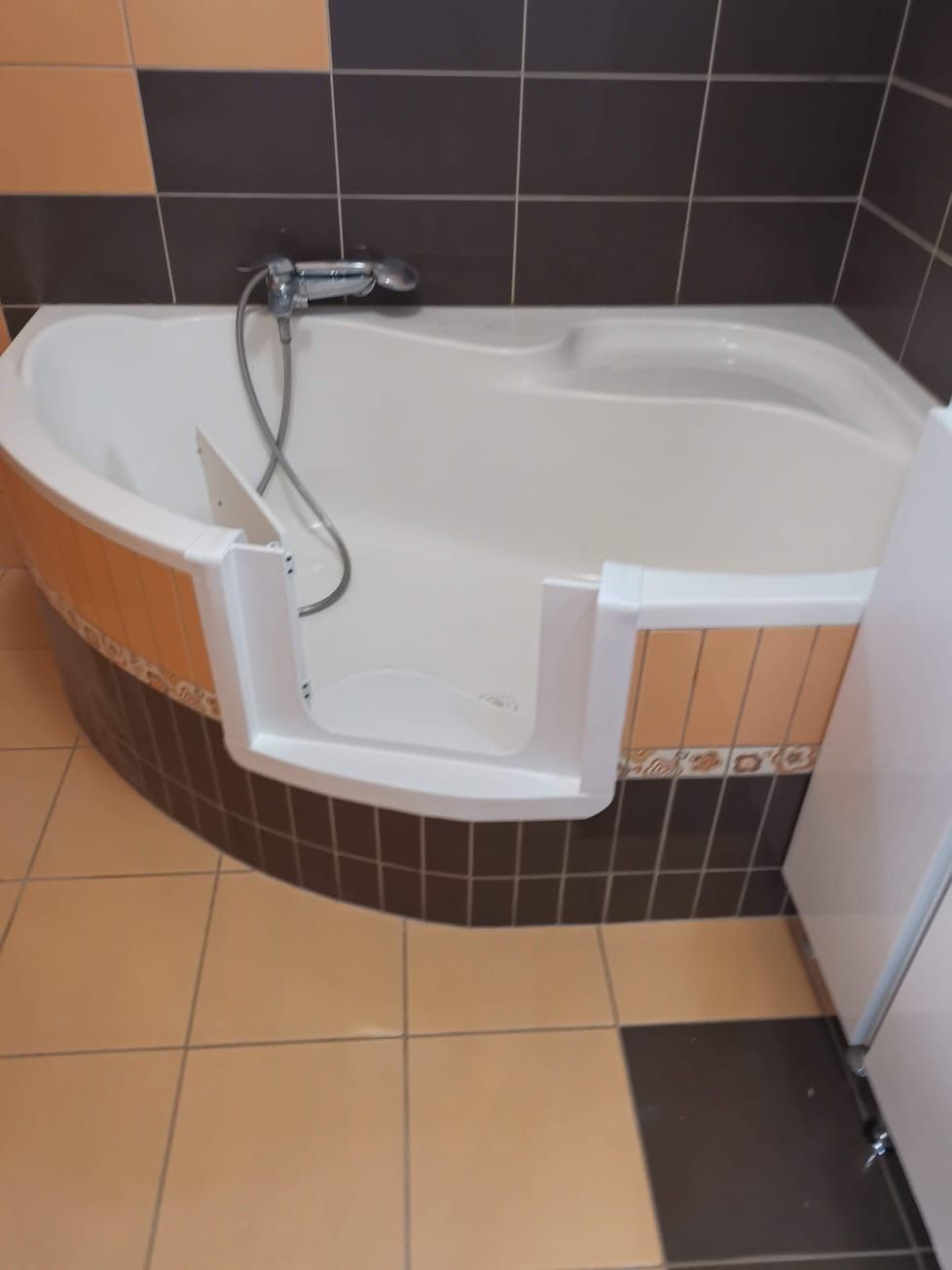 Baddeur in een hoekbad met donkerbruine tegels